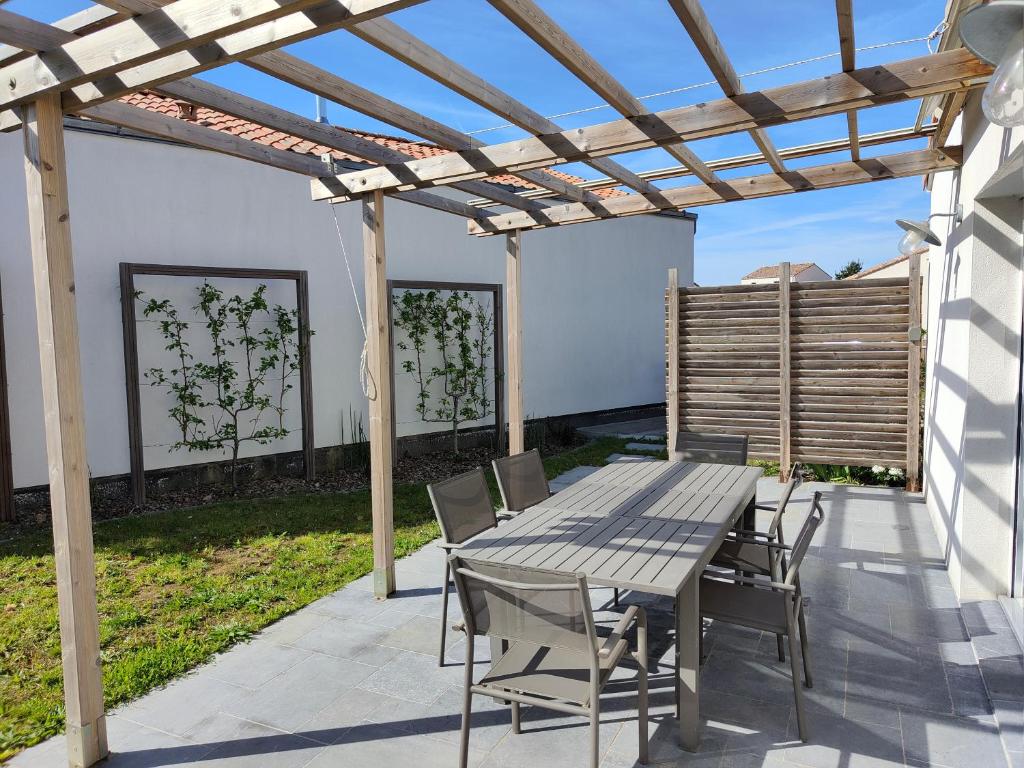 un patio avec une table et des chaises sous une pergola dans l'établissement La tranquille escale, à Bretignolles-sur-Mer