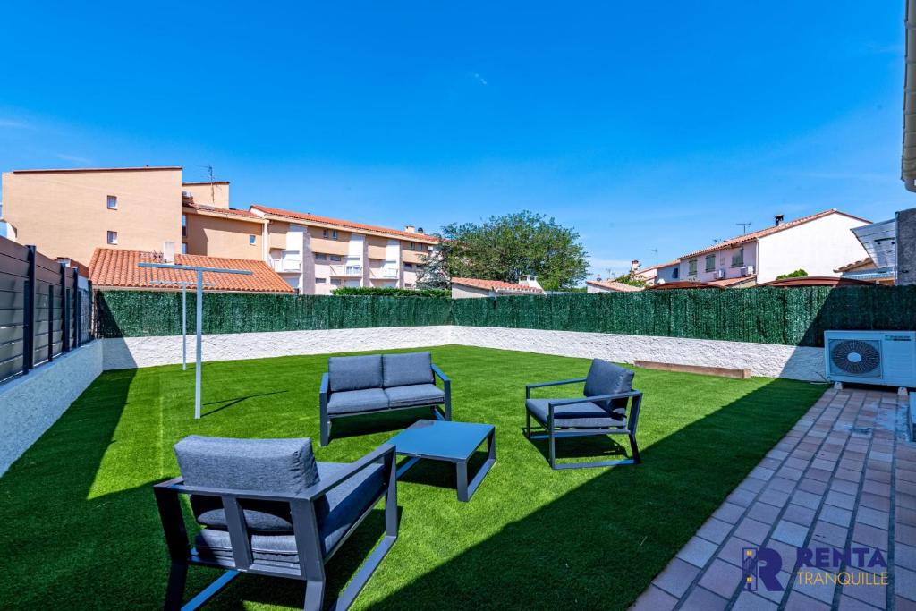 a patio with two chairs and a table and grass at La Perle WIFI Plain Pied Proche Mer in Saint Cyprien Plage