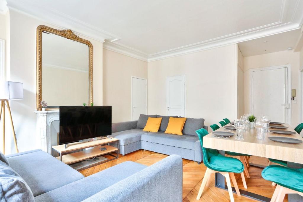 a living room with a blue couch and a table at Arc de Triomphe Superbe Appartement Paris in Paris