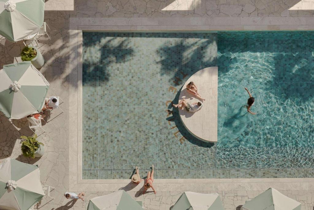 an overhead view of a pool with people in chairs and umbrellas at The Calile Hotel in Brisbane