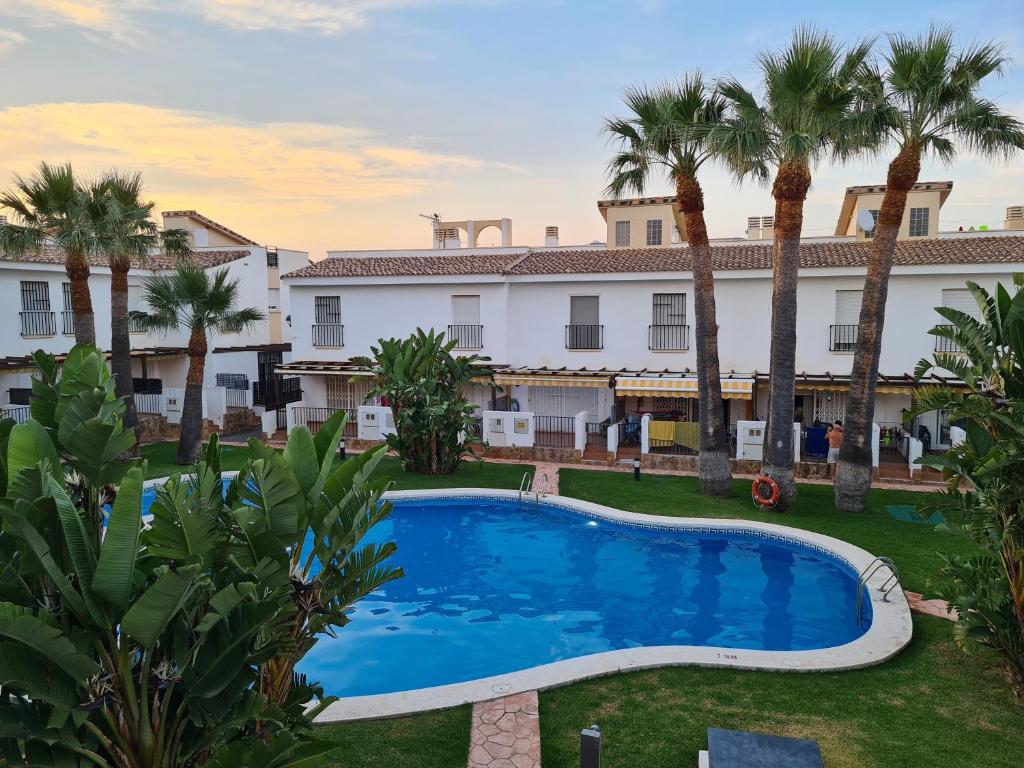 a pool in front of a building with palm trees at Siente el relax. in Alcossebre