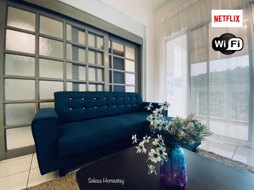 ein blaues Sofa im Wohnzimmer mit Fenster in der Unterkunft OCEAN ESCAPE@Selesa Hillhomes, Bukit Tinggi Pahang in Bentong