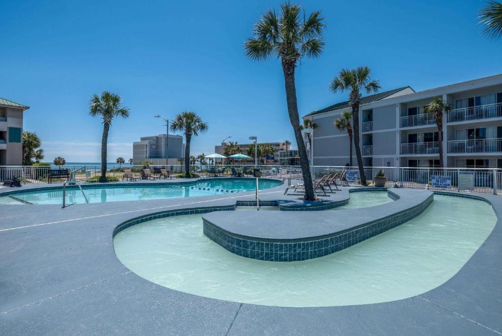 a swimming pool with palm trees in a parking lot at The Sandbar Hotel, Trademark Collection by Wyndham in Myrtle Beach