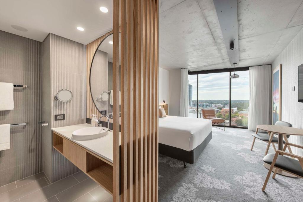 a hotel room with a bed and a bathroom at Vibe Hotel Adelaide in Adelaide