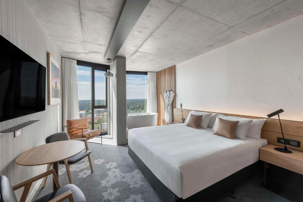 アデレードにあるVibe Hotel Adelaideのベッド、デスク、テレビが備わるホテルルームです。