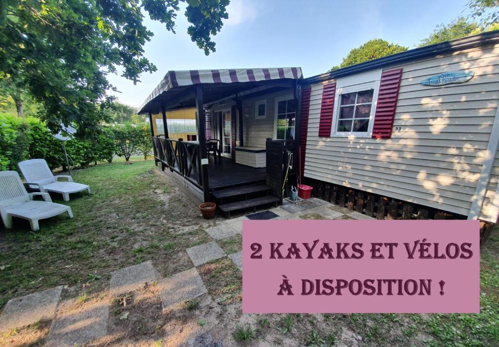 une petite maison avec une véranda et un panneau dans l'établissement Mobil Home, à Sainte-Eulalie-en-Born