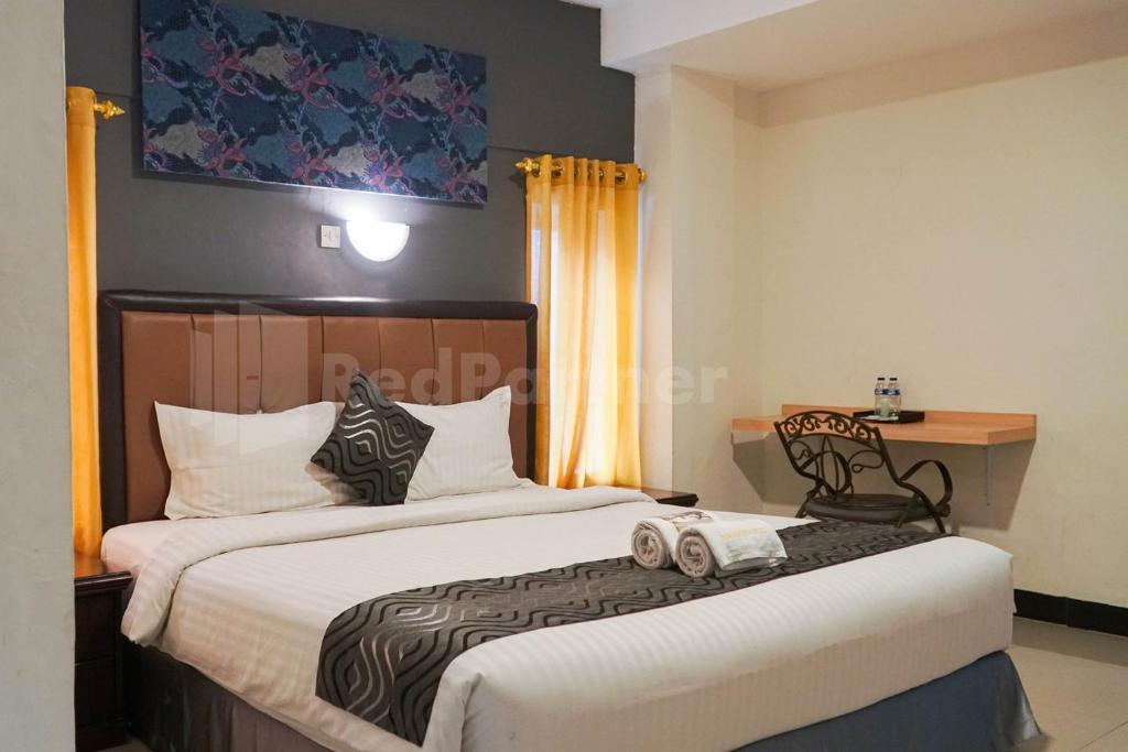 Un dormitorio con 2 camas y una silla. en New Gentala Hotel Mitra RedDoorz, en Medan