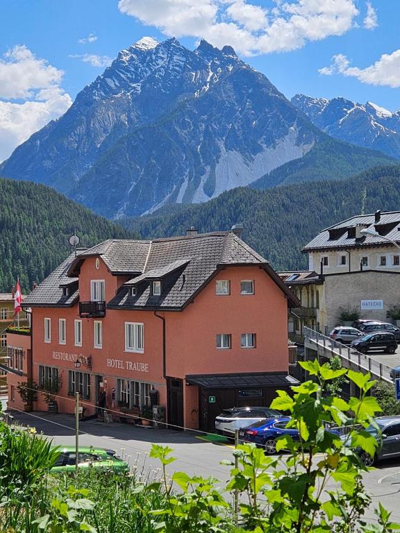 a building with a mountain range in the background at Hotel Traube in Scuol