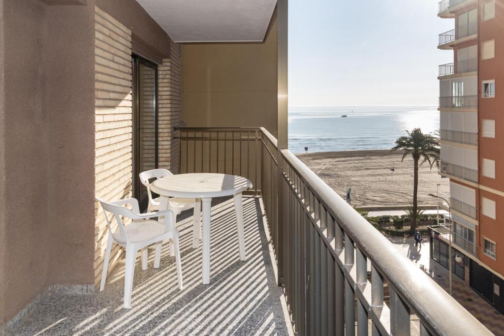 a balcony with a table and chairs and the beach at Provence, 5º-18 in Cullera