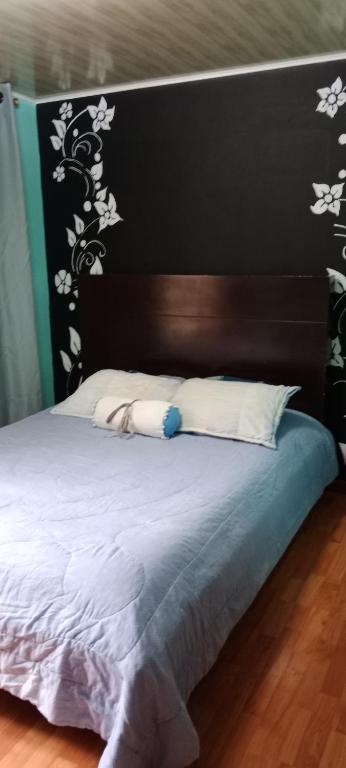 uma cama com cabeceira preta e almofadas brancas em Dulce sueños baño compartido em Chía