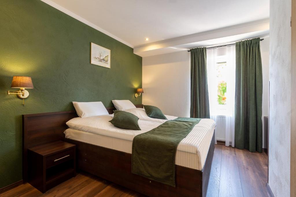 a bedroom with a large bed with green walls at Jupa's Hotel in Düsseldorf