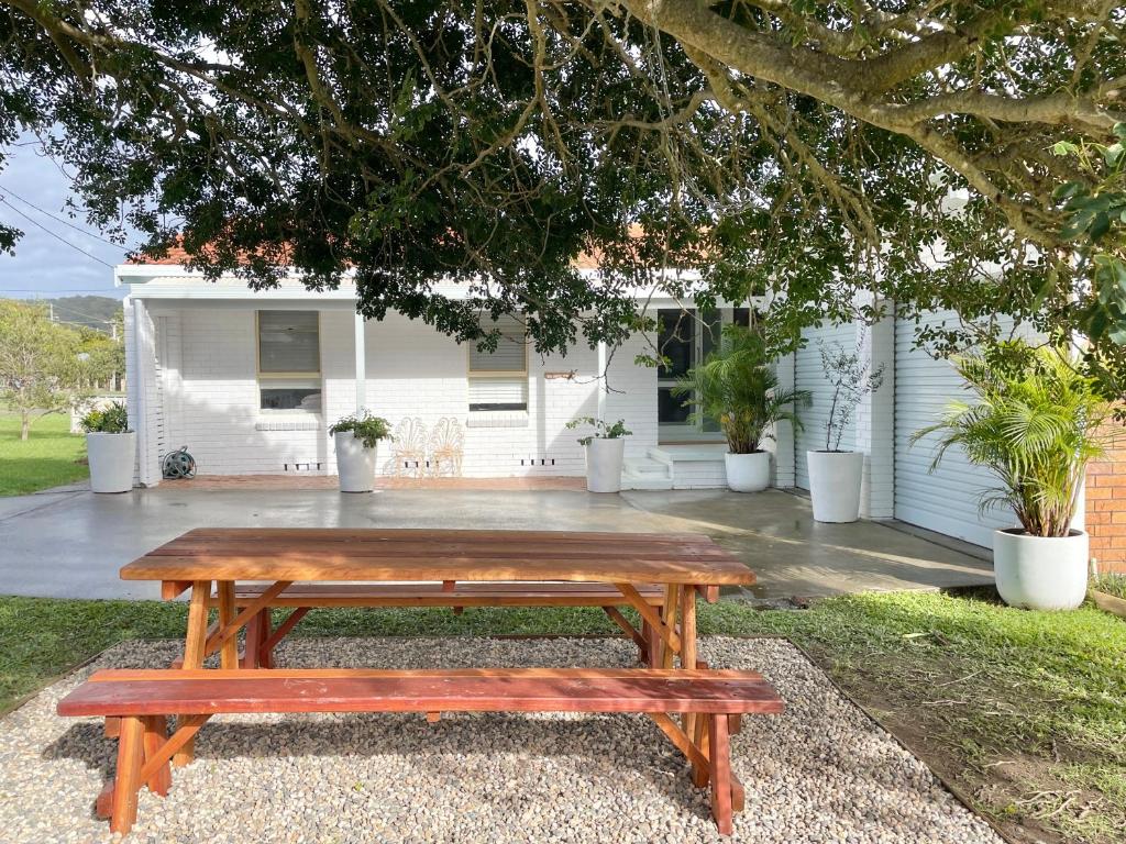 una mesa de picnic de madera frente a una casa en Sunny Corner Holiday Home, en Crescent Head