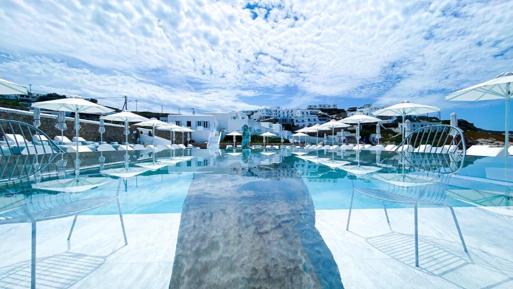 a swimming pool with chairs and umbrellas at Mykonos Bay Resort & Villas in Mýkonos City