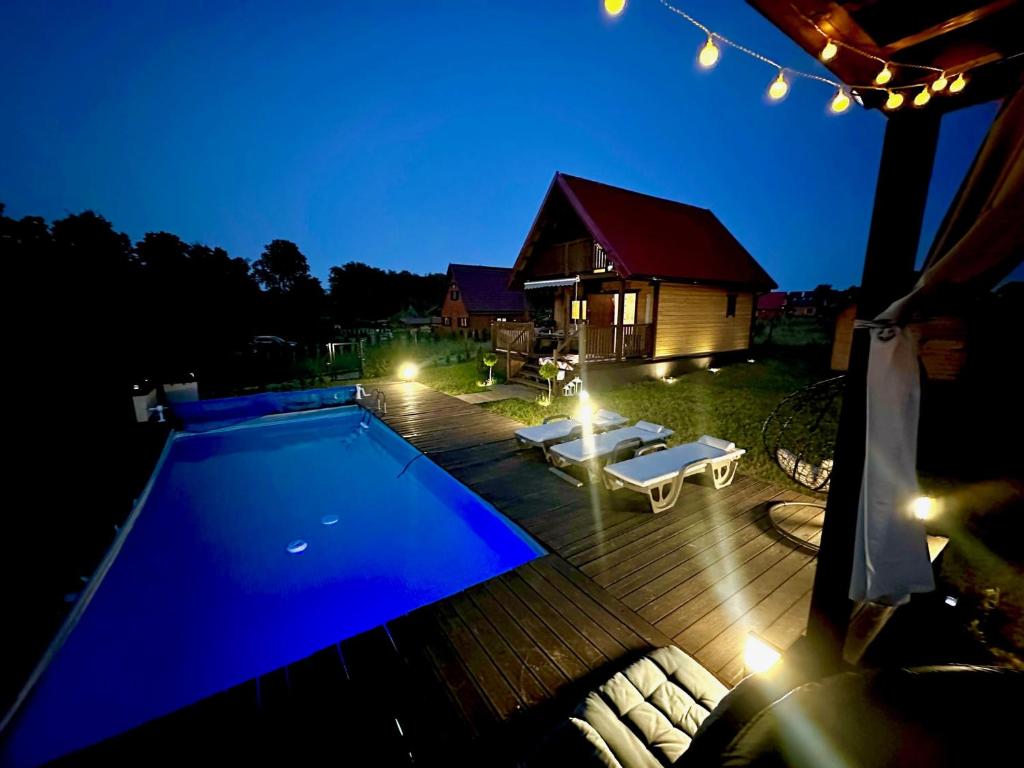 a backyard with a swimming pool at night at Domek letniskowy Aster z basenem i jacuzzi in Małdyty