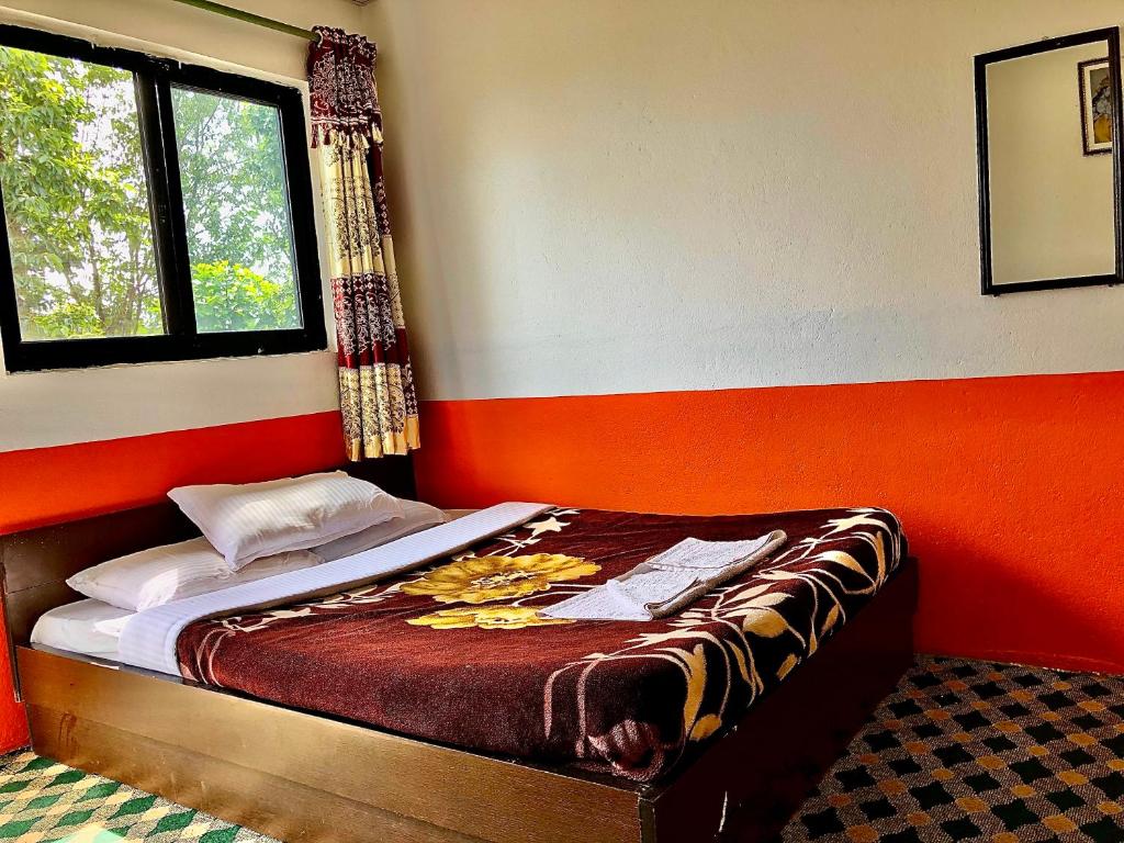 a bedroom with a bed with an orange and white wall at New Araniko Resort (P) Ltd in Chautara