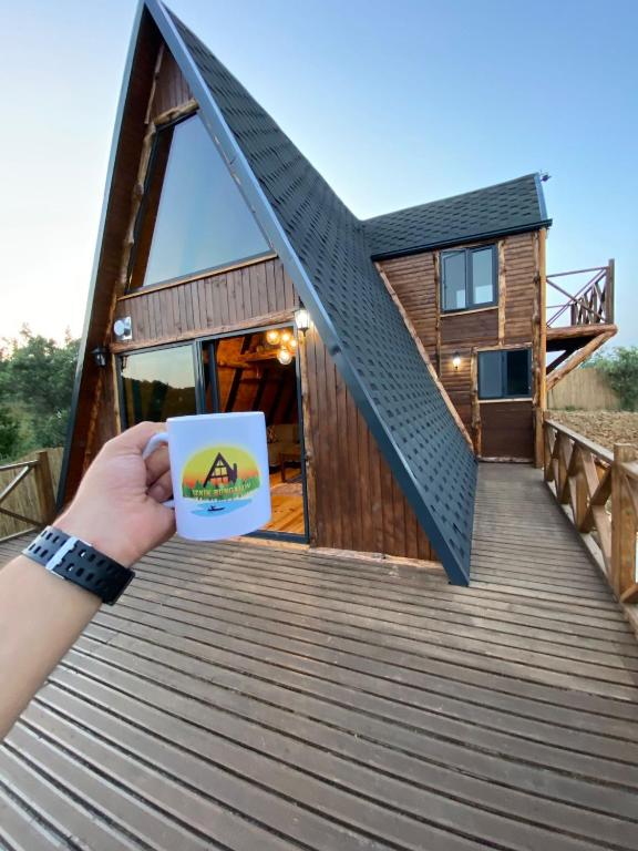 una persona sosteniendo una taza de café frente a una cabaña en Bungalow In Iznik, en İznik