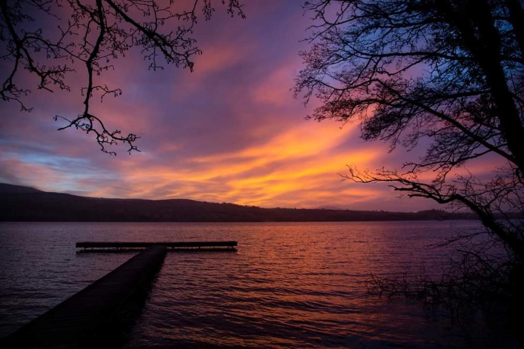 a sunset over a body of water with a dock at Leaba On The Lake in Killaloe