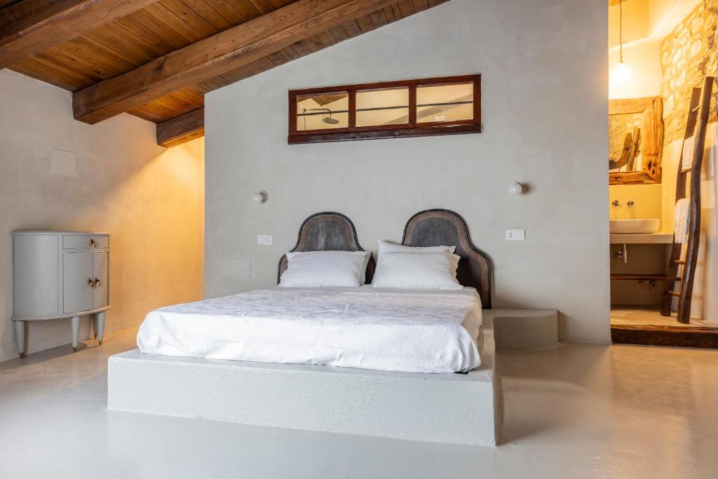 um quarto com uma cama com lençóis brancos e uma janela em Donna Rina - suggestiva casa nel centro storico em Colledimezzo