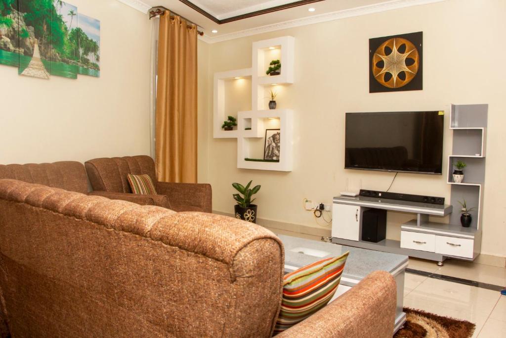 a living room with two couches and a flat screen tv at Rare APT for solo and couple Travellers in Kampala