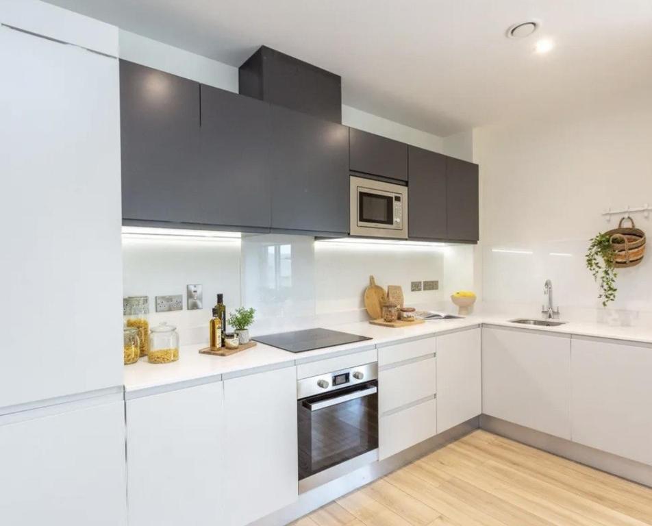 a white kitchen with black cabinets and a sink at Deluxe Seaview Apartment in Dun Laoghaire