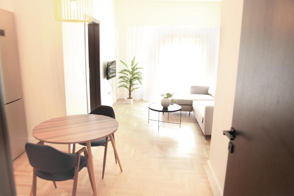 uma sala de estar com uma mesa e cadeiras e um sofá em Citybreak Apartments 301 em Atenas