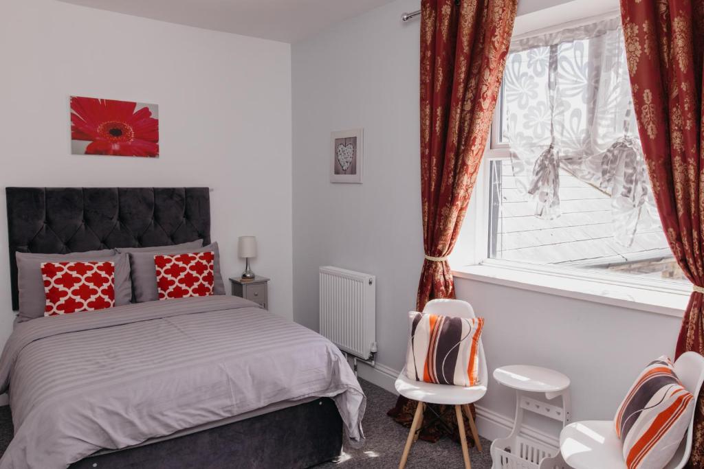 een slaapkamer met een bed met rode kussens en een raam bij Sherwood Hotel in Margate