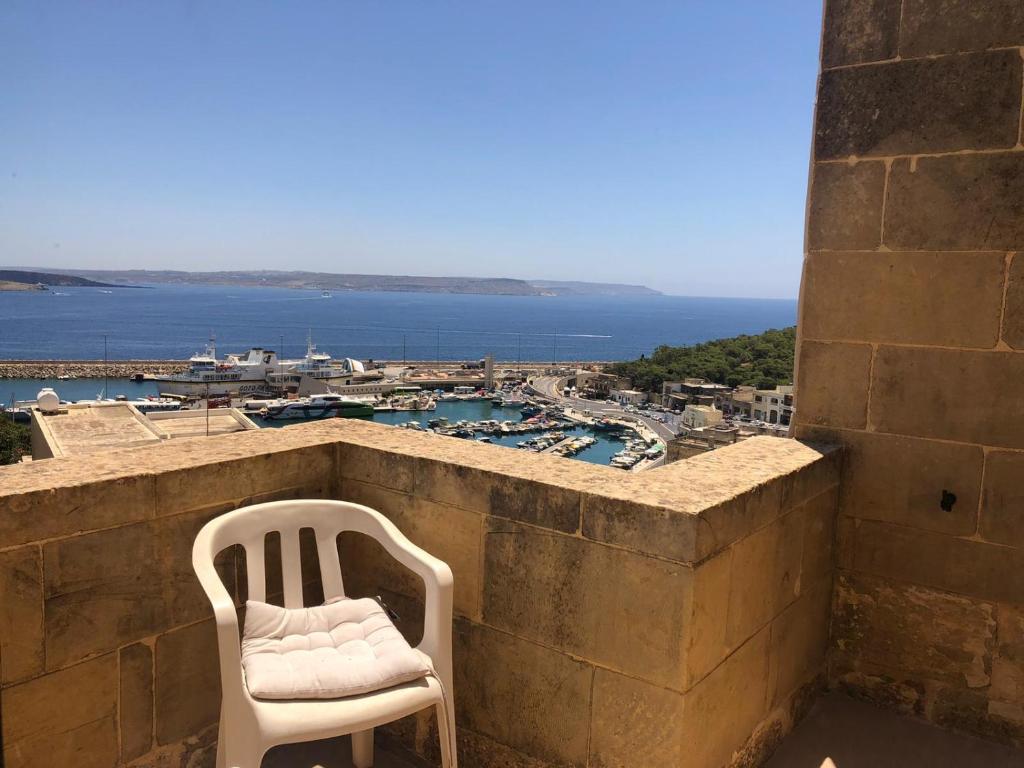 een witte stoel bovenop een stenen muur bij B&b Seaview terrace in Għajnsielem