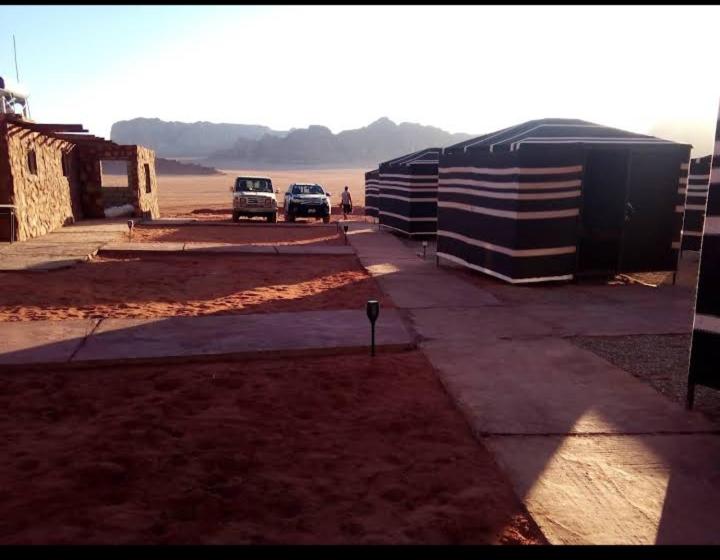 two cars driving down a road next to a building at Wadi rum Rozana camp in Wadi Rum