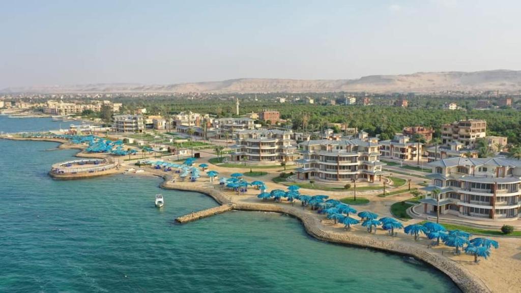 una vista aérea de un complejo con sombrillas azules y agua en Fanara Apartments Armed Forces, en Fayed