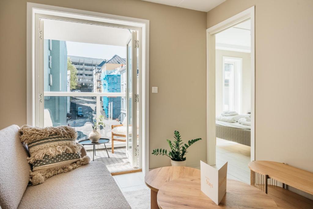 a living room with a couch and a large window at Stay Urban - Scandinavian Comfort with Private Balcony in Bergen