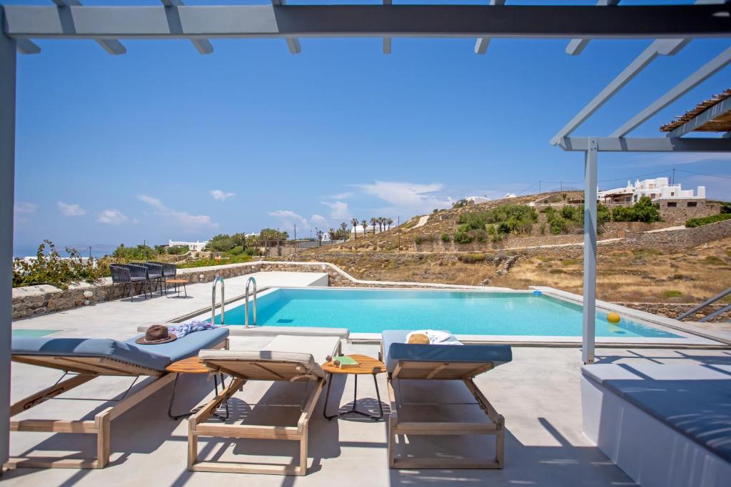 a person laying on a chair next to a swimming pool at Terra White Seaview Pool Apartments & Suites in Mikonos