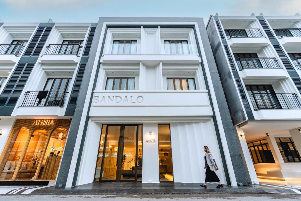 巴東海灘的住宿－Bandalo Boutique Hotel，女人走过建筑物的前面