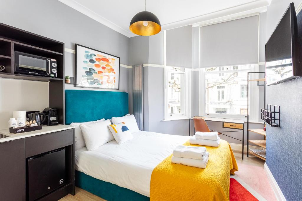 1 dormitorio con 1 cama con manta amarilla en Kensington Rooms - Philbeach Gardens, en Londres