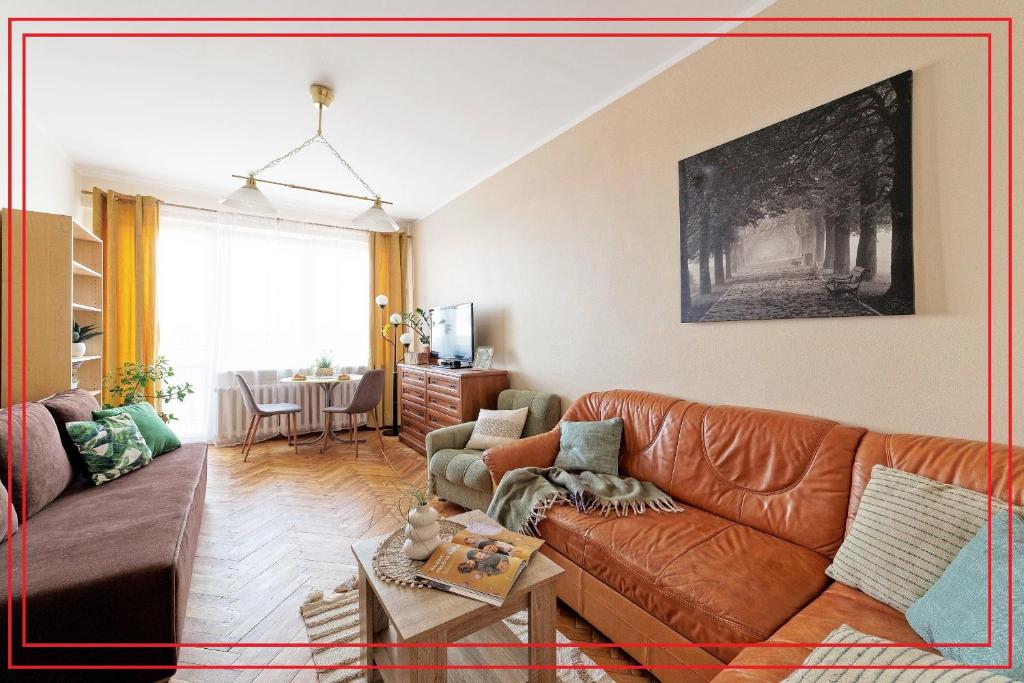 sala de estar con sofá de cuero marrón y mesa en Apartament 2 pokoje blisko morza 1000 metrów w Gdańsku, en Gdansk