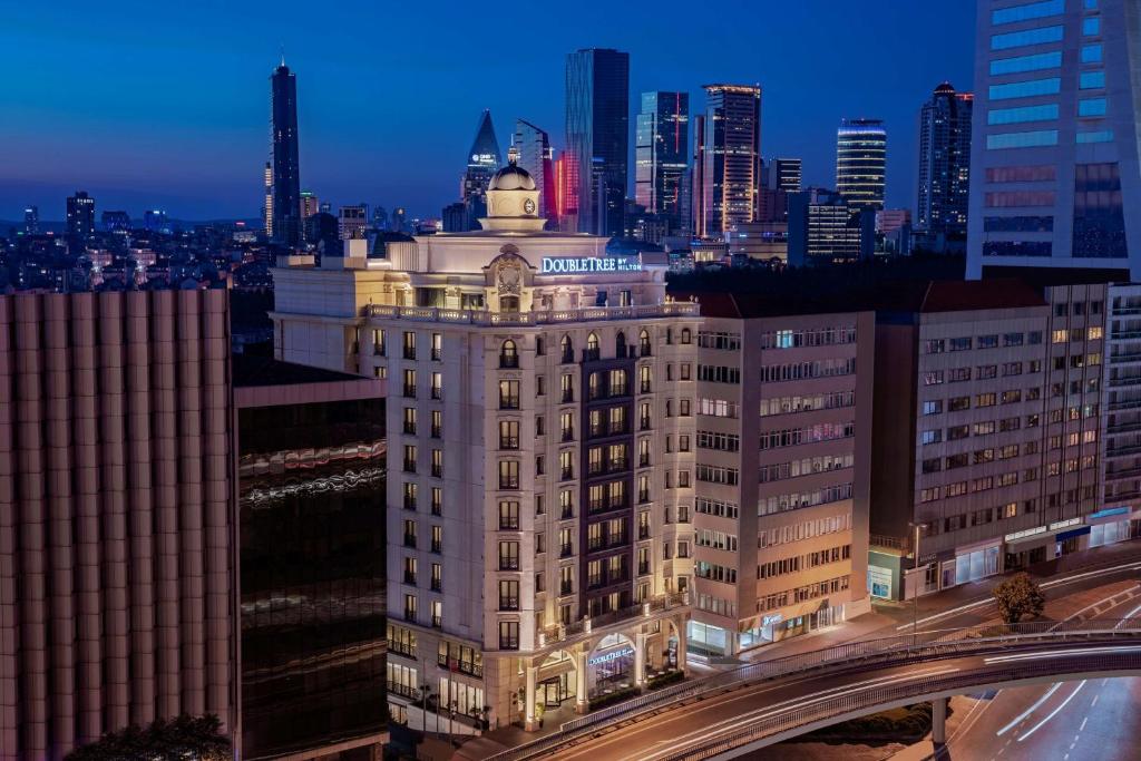 um edifício iluminado com uma cidade ao fundo em DoubleTree by Hilton Istanbul Esentepe em Istambul