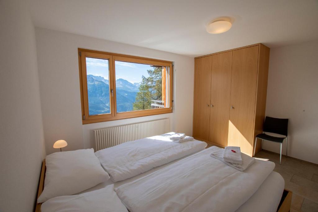 a bedroom with two white beds and a window at Haus Bella Vista in Riederalp