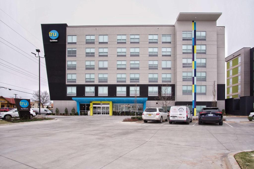俄克拉何马城Tru By Hilton Oklahoma City Nw Expressway的一座大楼，停车场里停满了汽车