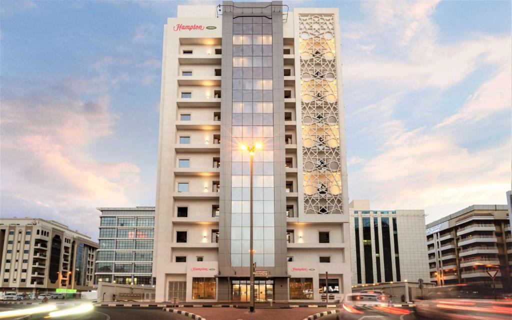 Hampton By Hilton Dubai Al Barsha في دبي: مبنى ابيض طويل عليه ساعه