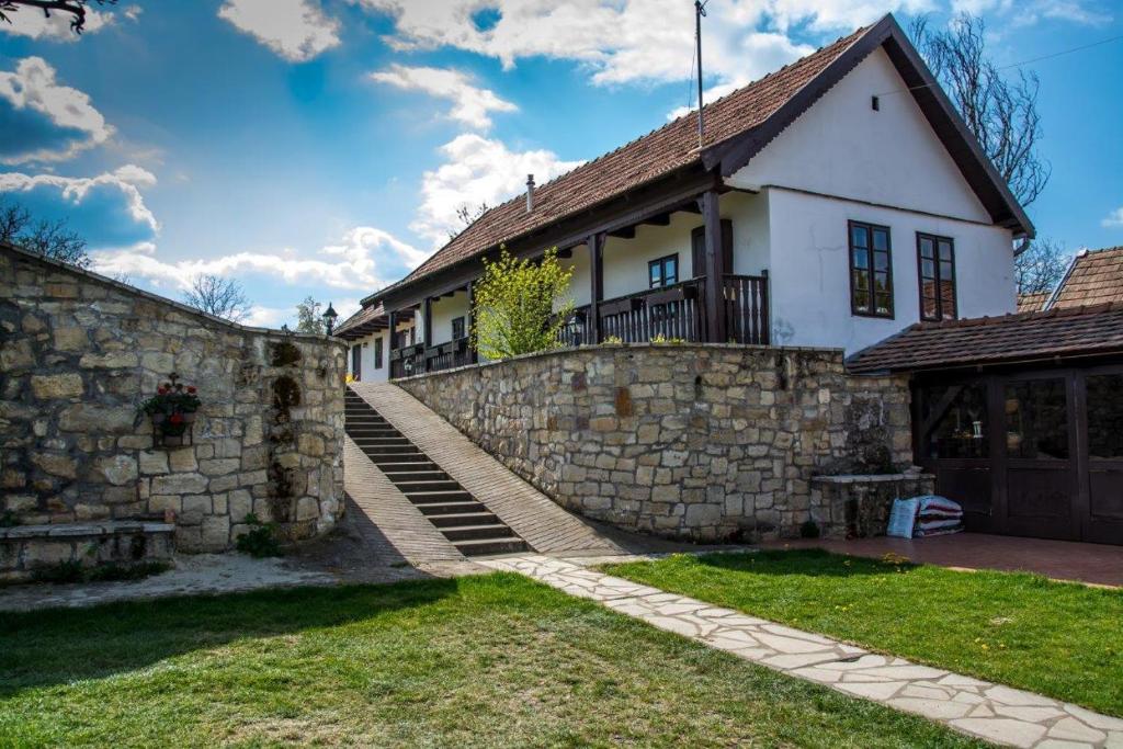 ein Haus mit einer Steinmauer und einem Zaun in der Unterkunft Kemencés Vendégház in Vanyarc