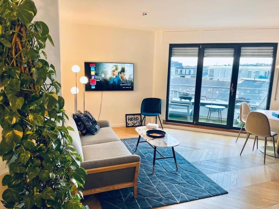 ein Wohnzimmer mit einem Sofa und einer großen Pflanze in der Unterkunft Luxury 1 bedroom in Center with Terrace & Parking-51B in Luxemburg (Stadt)