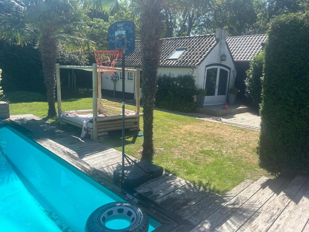 ein Basketballkorb in einem Hof mit einem Haus in der Unterkunft Tuinhuis met gebruik van zwembad in Aerdenhout