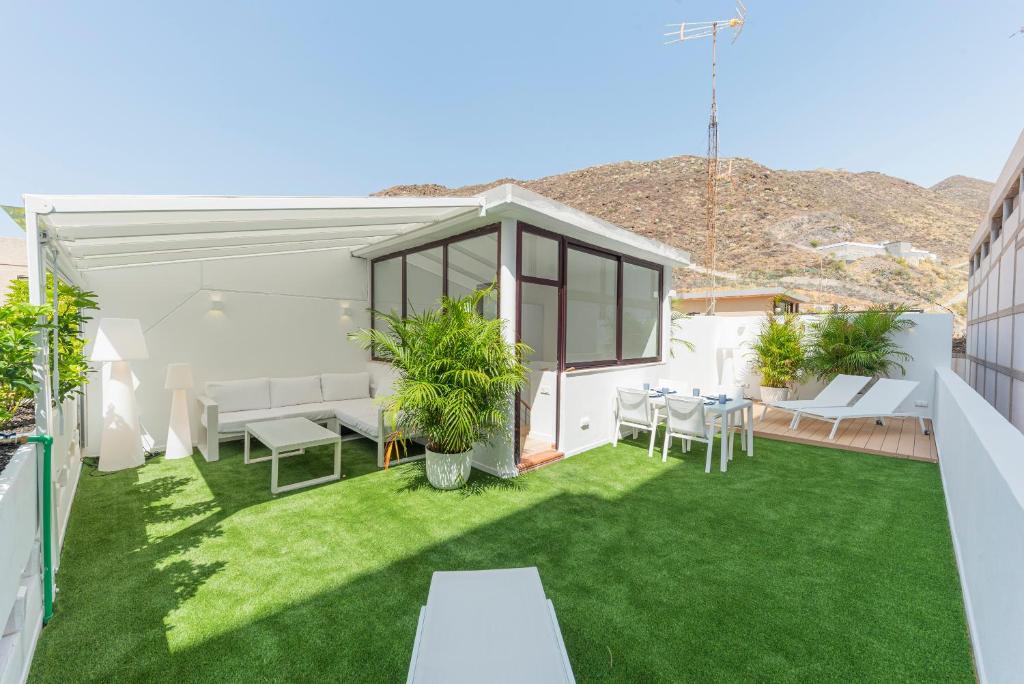 un pequeño patio trasero con césped verde y muebles blancos en The Terraces Luxury Penthouses, 3B, en Santa Cruz de Tenerife