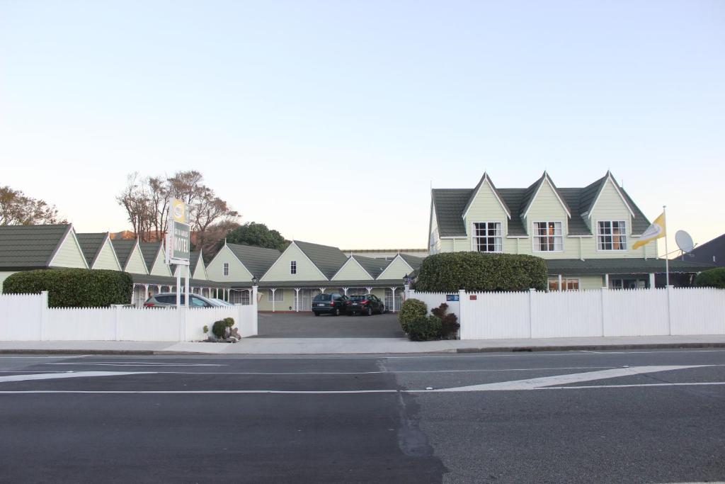 a row of houses with a white fence and a street at ASURE Green Gables Motel in Lower Hutt