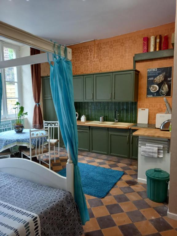 una cocina con armarios verdes y una cama en una habitación en Bohemian Studio bedroom en Pontrieux