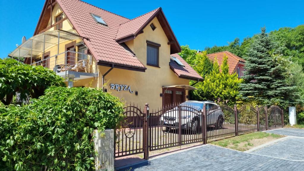 une maison avec une clôture et une voiture garée devant dans l'établissement Bryza, à Trzęsacz
