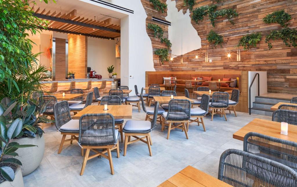 an empty restaurant with wooden tables and chairs at Canopy West Palm Beach - Downtown in West Palm Beach