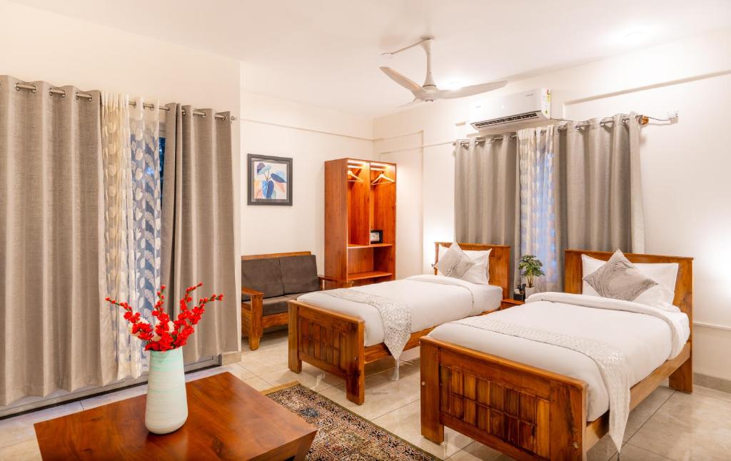 バンガロールにあるThe Silver Chimes Suitesのベッド2台とテーブルが備わるホテルルームです。