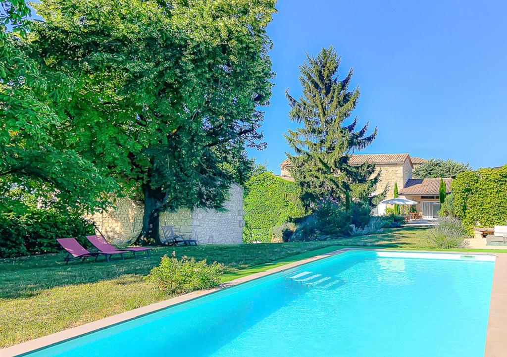 una piscina en un patio con 2 sillas moradas en L'Envolée Sauvage, en Cordes-sur-Ciel
