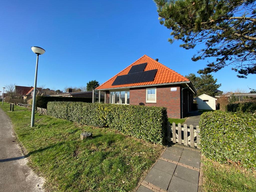 a house with an orange roof and a fence at Previnaireweg 25 in Callantsoog