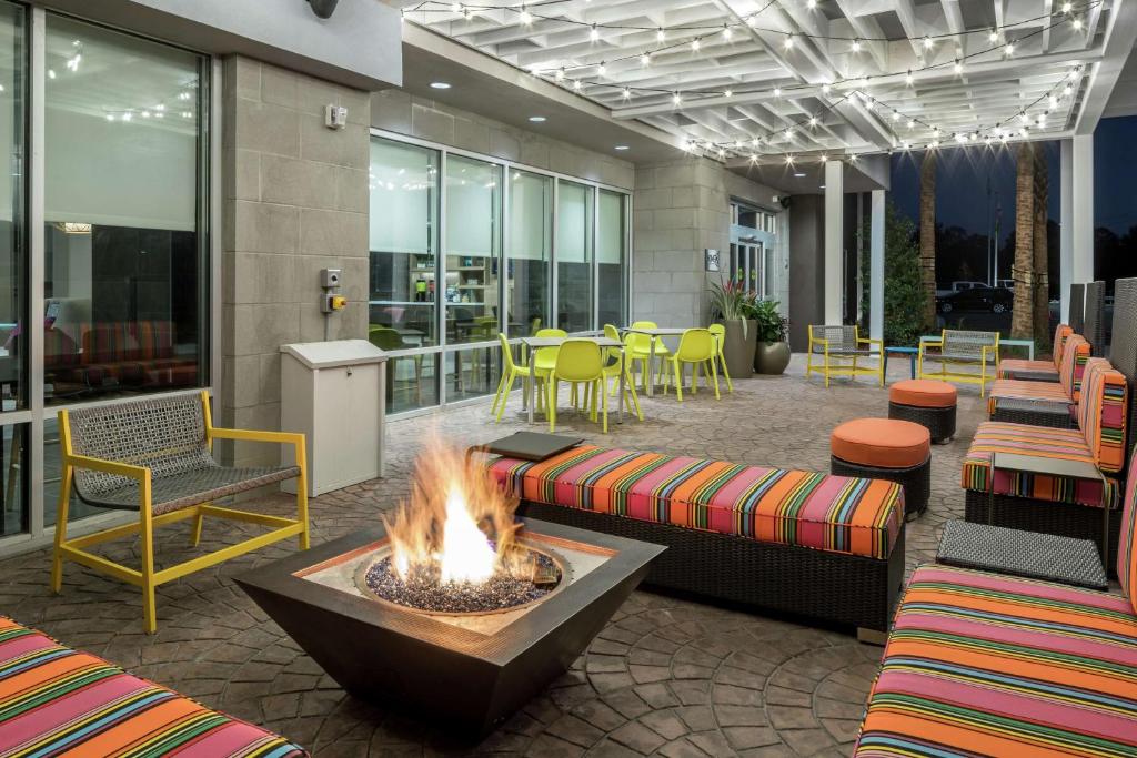 hol z miejscem na ognisko, stołami i krzesłami w obiekcie Home2 Suites By Hilton Jacksonville Airport w mieście Jacksonville